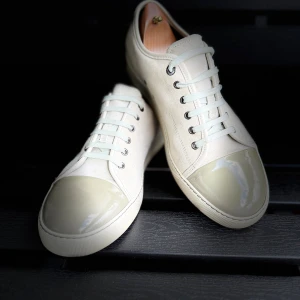 Lanvin skor👞 - Snygga ljus grå  sneakers med ovandel i mocka och en unik, glansig lackad tå i ljusbeige. Skorna har vita snören, metallöljetter och en platt sula. Perfekta för dig som gillar stilrena men ändå annorlunda detaljer på dina skor.