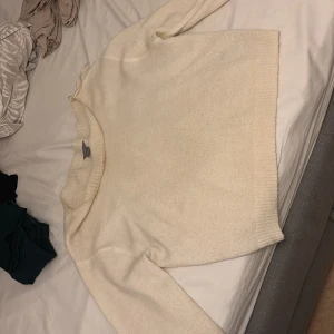 Beige stickad tröja från Lindex - Mysig vit stickad tröja från Lindex i storlek S. Tröjan har en enkel och clean design med ribbade muddar vid hals, ärmslut och nederkant. Perfekt för lager-på-lager och chill dagar. Passar dig som gillar basic och neutrala färger.