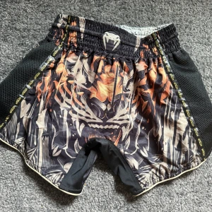 Svarta träningsshorts från Venum - Säljer ett par riktigt snygga Muay thai shorts ifrån venum i tiger kollektionen. Shortsen är helt oanvända med prislapp kvar. Priset går att diskutera 