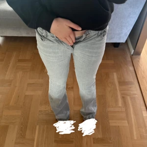 Ljusgrå bootcut jeans - Säljer ett par ljusgrå jeans med bootcut passform. Jeansen har klassisk femficksdesign, knapp och dragkedja fram samt raka ben som blir lite vidare nedtill. Storlek 164.