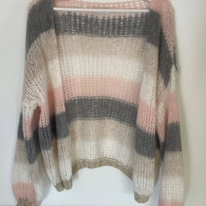 Randig stickad kofta  - Supermysig stickad kofta med breda ränder i grått, vitt, beige och ljusrosa. Koftan är oversized och har en guldig detalj i ärmarna. Knappt använd💗