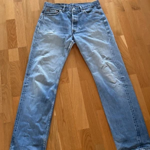 Levis jeans - Fina 501 Levis jeans i fin ljusblå färg. Lite hål finns, kolla bilderna, ett lagat hål på ena knäet men som man knappt lägger märke till, skriv för mer info! W34 L34