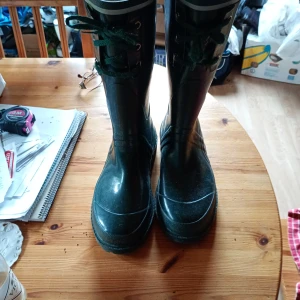 Mörkgröna höga stövlar med snörning stl 41 - Snygga mörkgröna höga stövlar med grov sula och snörning framtill. Tillverkade i syntetmaterial med rund tå och platt sula. Perfekta för regniga dagar eller utomhusaktiviteter. Sparsamt använda i stl 41.