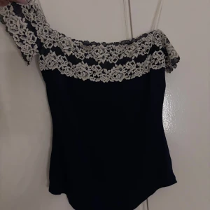 Marinblå  body Intimissimi! - Supersnygg mörkblå body med off-shoulder design och bred vit spets längs överdelen. Aldrig använd men köpt av nån på pllick så den är inte i nyskick! Men har inga defekter! I toppen skick🫶🏻