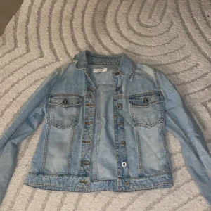 Klassisk ljusblå jeansjacka - Säljer en klassisk ljusblå jeansjacka med snygga bröstfickor och knappar framtill. 