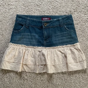 Jeanskjol med volang - Supersöt kort jeanskjol från Denim Co med volang i beige bomullstyg nertill. Kjolen har klassiska jeansfickor fram och bak, bälteshällor och knappstängning.🫶🏻