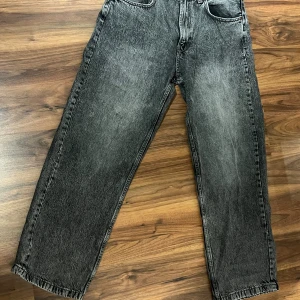 Svarta wide jeans från Zara - Säljer ett par svarta jeans från Zara med cool tvättad look och bred passform. Modellen har raka ben, klassiska fem fickor och knappgylf. Perfekt för dig som gillar avslappnad stil och vill ha jeans med lite edge.