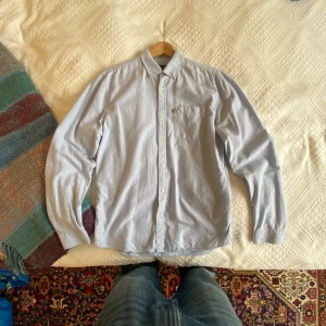 Ljusblå skjorta från Lexington M - Snygg ljusblå skjorta från Lexington i slim fit-modell. Tillverkad av ekologisk bomull, med klassisk button down-krage, bröstficka och vita knappar. Perfekt för dig som gillar stilrena och fräscha plagg.