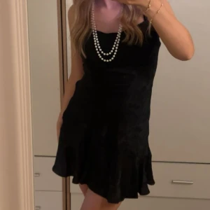 Svart kort klänning - Supersnygg svart klänning med volang nertill och smala axelband. Lätt blommigt mönster på💕🖤Använd 1 gång