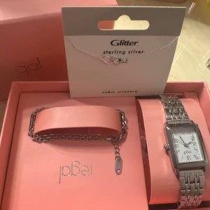 Smyckeset Regal & Glitter silver - Säljer ett smyckeset med ett silvrigt armband från mockberg (se bild)  och en klocka från Regal samt ett halsband från Glitter i äkta silver med två hjärtan, varav ett är dekorerat med cubic zirconia. Perfekt för dig som gillar stilrena accessoarer med en touch av bling. Allt är nyskick och med prislapp på, den levereras med den rosa boxen, skulle man vilja ha något enskilt är det bara att skriva😊😊