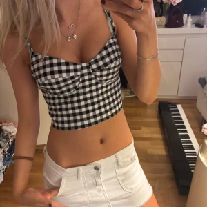 Svartvit rutig croppad korsettopp - Säljer en croppad topp med svart vitt rutigt mönster!! Super snygg och perfekt till fest!