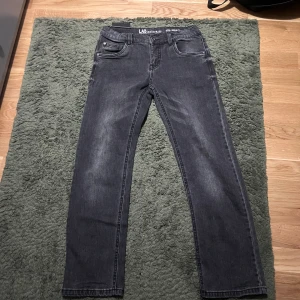 Mörkgrå jeansbyxor från LAB - Snygga mörkgrå jeansbyxor från LAB med klassisk femficksdesign och raka ben. Jeansen har en diskret tvättad look och är tillverkade i mjukt jeansmaterial som sitter skönt hela dagen. Perfekta för dig som gillar en stilren och enkel vibe.