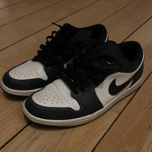 Nike Air Jordan 1 Dark Teal - Säljer ett par Nike Air Jordan 1 Low i Dark Teal och vitt skinn med klassisk Swoosh på sidan och Air Jordan-logga broderad på hälen. Låga sneakers med svart snörning. Perfekta för dig som gillar streetwear och ikoniska modeller. Storlek 43