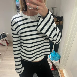 Randig stickad tröja i svart och vitt - Säljer en stickad tröja med svarta och vita ränder. Tröjan har lång ärm, rund halsringning och en lite lösare passform. Perfekt för dig som gillar en chill och stilren look. Passar både till jeans och mjukisbyxor.