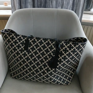 By Malene Birger  - Stor shoppingväska i svart och vitt med grafiskt rutigt mönster. Väskan har svarta handtag i skinn och rymligt brunt innerfoder. Perfekt för dig som vill ha plats för allt du behöver under dagen. Snygg och stilren design som sticker ut.