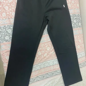 Svarta byxor från Ralph Lauren - Svarta byxor från Ralph Lauren med klassisk rak passform och diskret broderad logga på höften. Byxorna är stilrena och passar perfekt till en avslappnad men ändå snygg look. Materialet känns mjukt och bekvämt.