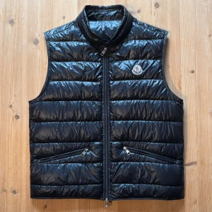 Moncler Gui Gilet - Moncler Gui vest in Black🖤, in size moncler size 2 which corresponds to small-medium, can send me a picture if desired, selling this iconic moncler model Gui vest. New price is 9250kr. no signs of wear, completely clean, I'm moving and need to get it away, the zipper is a bit difficult at times especially at the bottom, maybe there is a quick fix at the tailor for it to work optimally, but it works if you are patient, you can find these in the price range from 3.5-6k so make yourself a bargain!