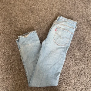 Levi's 501 ljusblå jeans straight fit - Ljusblå Levi's 501 jeans med klassisk straight fit och femficksdesign. Jeansen har den ikoniska röda Levi's-lappen på bakfickan och är tillverkade i slitstarkt bomullsjeans. Perfekta för en avslappnad och tidlös look.