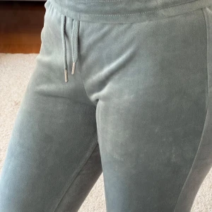 Turkosa/gråa mjukisbyxor med snörning - Mysiga grå/ turkosa mjukisbyxor i mjukt fleecematerial med hög midja och raka ben. Byxorna har snörning i midjan och två bakfickor. Perfekta för chill dagar hemma eller när du vill vara extra bekväm.