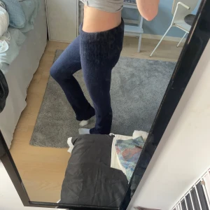 Mörkblå stickade byxor - Mörkblå stickade byxor med bred ribbad mudd i midjan. Byxorna har en rak passform med lätt utsvängda ben och är gjorda i ett mjukt, stickat material som känns riktigt skönt mot huden. Perfekta för en chill och avslappnad look. Från fina tricot, supersköna och perfekta till vintern!