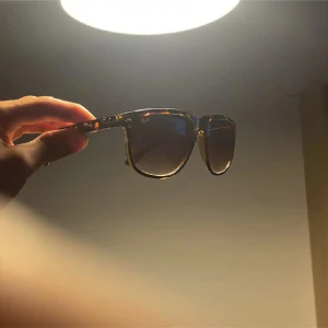 Ray-Ban solglasögon brunmelerad - Snygga Ray-Ban solglasögon med brunmelerad båge och mörka glas. Klassisk och tidlös design med Wayfarer-inspirerad form. Perfekta för att lyfta din stil under soliga dagar.