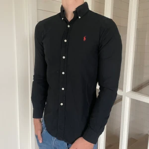 Ralph lauren skjorta - Säljer denna riktigt snygga svarta Ralph lauren skjorta! Den är i mycket bra skick, storlek S modell slim fit, den är 75 vem lång och 45 cm bred under armhålorna, hör gärna av dig vid frågor!