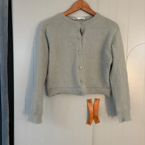 Ljusgrön stickad kofta från Zara - Mysig ljusgrön stickad kofta från Zara med rund halsringning och knappar framtill. Koftan har långärmad passform och ribbade muddar vid ärmslut och nederkant. Ända defekten är att knapparna är lite hängiga:( den är även ganska lite för att vara storlek M.