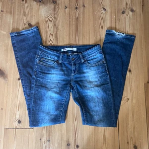 Blå raka jeans från ONLY - Säljer ett par blå skinny jeans från ONLY med snygga slitningar och klassisk femficksdesign. Jeansen har låg midja och är tillverkade i stretchigt denim för en tight passform. Perfekta för dig som gillar en smal siluett och cool tvätt.