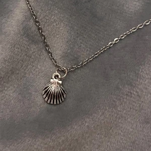 Choker Snäckskal Halsband Silver Imitation  -  Så fin choker med en liten berlock av ett snäckskal. Trädd på kedja i silverimitation, justerbar 35-40 cm. Berlocken är ca 1 x 1 cm. 
