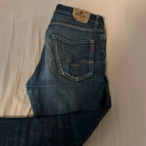 Blå jeans från Replay, storlek 14A - Snygga blå jeans från Replay med klassisk femficksdesign och coola detaljer som kontrastsömmar och Replay-logga på bakfickan. Jeansen har en autentisk tvättad look och är tillverkade i slitstarkt denim. Perfekta för dig som gillar en tidlös och avslappnad stil.