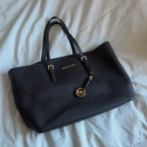 Chokladbrun Michael Kors axelväska i skinn - Mindre repor samt lös tråd i ena handtaget. Chokladbrun väska med guldiga detaljer.