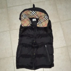 Burberry jacka - Hör har vi en skön Burberry jacka med den klassiska Burberry materialet, fast på jackan vid kragen! Jackan är dyr men den är de efter som den är extremt varm dyr och ny den är oxå i storlek S för män finns även i XS! Jackan är dyr pågrund av att man som på bilden kan göra den till en väst ärmarna kommer med man kan bara fixa fast dom med en dragkedja där vid ärmen!