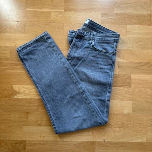 Grå raka jeans från Jack & Jones - Säljer ett par grå raka jeans från Jack & Jones, modell Loose/Chris. Jeansen har klassisk femficksdesign, rak passform och är tillverkade i slitstarkt denimtyg. Perfekta för dig som gillar en avslappnad och trendig look.