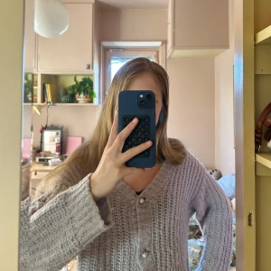 Ljuslila stickad kofta från Name It - Supermysig ljuslila stickad kofta från Name It med stora pärlknappar framtill. Koftan har en oversized känsla, grovstickad struktur och långa ärmar. Perfekt för lager på lager under kyliga dagar. Tröjan passar mig som är ca 155 cm. Tröjan är lite luddig men inga andra defekter.                 Skriv vid frågor! 💕