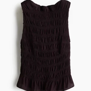 Svart smockad ärmlös topp - Säljer en mörklila ärmlös topp med smockad struktur och volangkant nedtill. Toppen har en lätt glansig finish och en mjuk, luftig känsla. Perfekt att styla med jeans eller kjol för en trendig look. Hör av er vid frågor! Jag accepterar dem flesta buden!