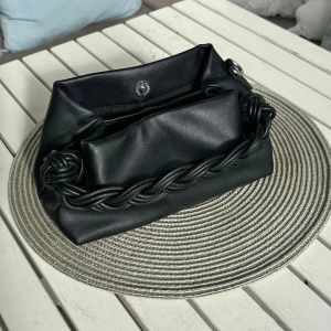 Svart axelväska med flätad detalj - Säljer en svart axelväska i skinnimitation med snygg flätad detalj framtill. Väskan har justerbar axelrem och stängs med magnetknapp. Perfekt storlek för det viktigaste och passar till många olika outfits.älskar denna väskan!💞