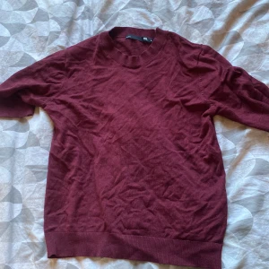 Vinröd tröja från 157, storlek M - En enkel och stilren vinröd tröja från 157 i storlek M. Tröjan har ribbade muddar vid hals, ärmslut och nederkant. Perfekt för lager-på-lager och funkar året runt. Materialet känns mjukt och är troligtvis bomull eller en bomullsblandning.