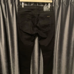 Nudie jeans - helvsvarta - Nudie jeans - helsvarta - skick 9/10, otroligt fint skick! - storlek: 32/32 - otroligt feta jeans, har även blivit eftertraktat med svarta jeans nu till vintern! - hör av er vid frågor! 