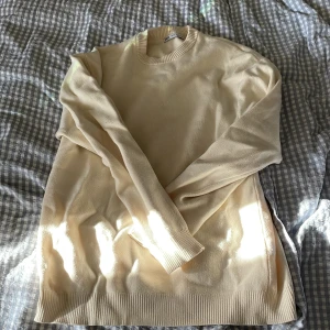 Beige stickad tröja från Zara - En stilren beige stickad tröja från Zara i storlek S. Tröjan har rund halsringning, ribbade muddar och är långärmad. Perfekt för lager-på-lager och enkel att matcha med olika outfits.