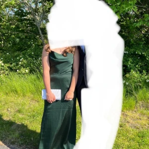 Mörkgrön balklänning - Snygg mörkgrön balklänning med smala axelband och draperad urringning framtill. Klänningen har en djup v-ringning i ryggen och är figurnära upptill med ett elegant fall. Endast använd en gång, (9ans bal), och har inga defekter! Som ny! Köpt på bubbleroom för om jag minns rätt, 1299 kr. Mitt pris för en i princip helt ny klänning: 800 kr, så 500 sparas!