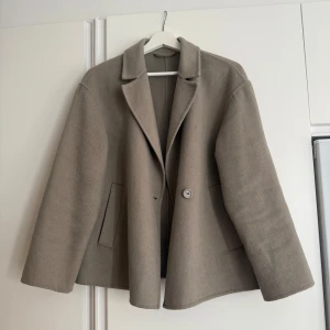 Kort kappa från Stockh LM - Materialet är en mix av ull och polyester, 