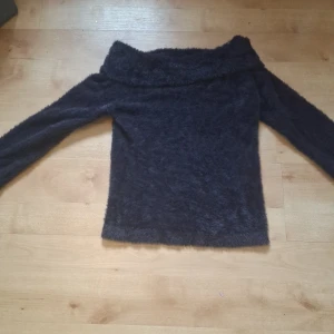 Mörkblå fluffig offshoulder-tröja Kappahl 170 - Mysig mörkblå offshoulder-tröja från Kappahl i fluffigt material. Tröjan har lång ärm och en bred, nedvikt krage som ger en snygg offshoulder-look. Perfekt för dig som vill ha något både bekvämt och trendigt.