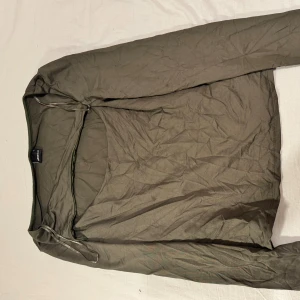 Olivgrön  topp från Gina Tricot - Säljer en olivgrön  topp från Gina Tricot med långa ärmar och rund hals. Toppen har en slim passform och är tillverkad i stretchigt syntetmaterial.