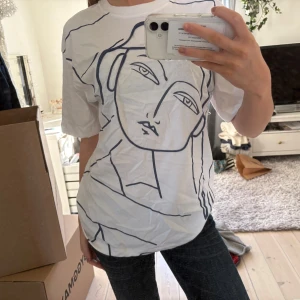 Vit cool t-shirt - Vit t-shirt i bomull med ett stort, konstnärligt ansikte tryckt i svart på framsidan. Helt oanvänd från ZARA.