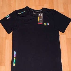 Svart Under Armour HeatGear t-shirt - Stilren svart t-shirt från Under Armour med reflekterande logga. Tillverkad i andningsbart material. Klassisk passform med korta ärmar och rund hals. Hör av dig vid fler frågor eller funderingar!