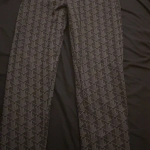 Mönstrade byxor från Lacoste - Snygga svarta byxor från Lacoste med grått geometriskt mönster. Byxorna har raka ben och är tillverkade i ett mjukt material som känns bekvämt. Perfekta för dig som vill sticka ut med en cool och unik stil.