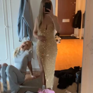 Glittrig långklänning från SHEINX - Supersnygg långklänning med djup v-ringning och smala axelband. Klänningen är täckt av glittriga paljetter och har en hög slits på sidan. Den är i en guldig champagne färg. Säljs inte längre i den färgen. Aldrig använd, endast provad. Perfekt för dig som vill sticka ut på bal eller fest.