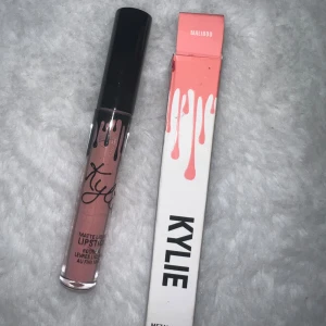 Kylie Matte Liquid Lipstick Maliboo - Kylie Matte Liquid Lipstick i färgen Maliboo. Snygg nude-rosa nyans med matt finish. Kommer i originalförpackning med svart lock och genomskinlig tub som visar färgen. Perfekt för dig som vill ha en trendig och hållbar läppfärg.