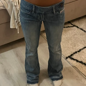 Lågmidjade blå bootcut jeans från Diesel - Säljer ett par blå jeans från Diesel med låg midja och bootcut-ben. Jeansen har två knappar i midjan, klassiska fickor och en liten logotypficka fram. Alla mått finns med, skriv vid fler frågor. Storlek 28 skulle säga en S. 100% bomull