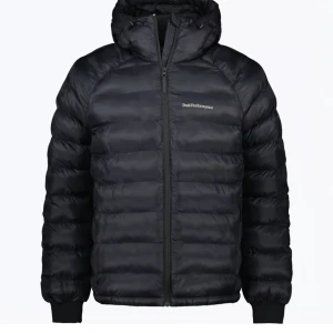 Svart dunjacka Peak Performance - Svart dunjacka från Peak Performance med huva och dragkedja framtill. Jackan har quiltad design, ribbade muddar och diskret logga på bröstet. Perfekt för kalla dagar med sin lätta och fluffiga känsla.💓nypris 3000